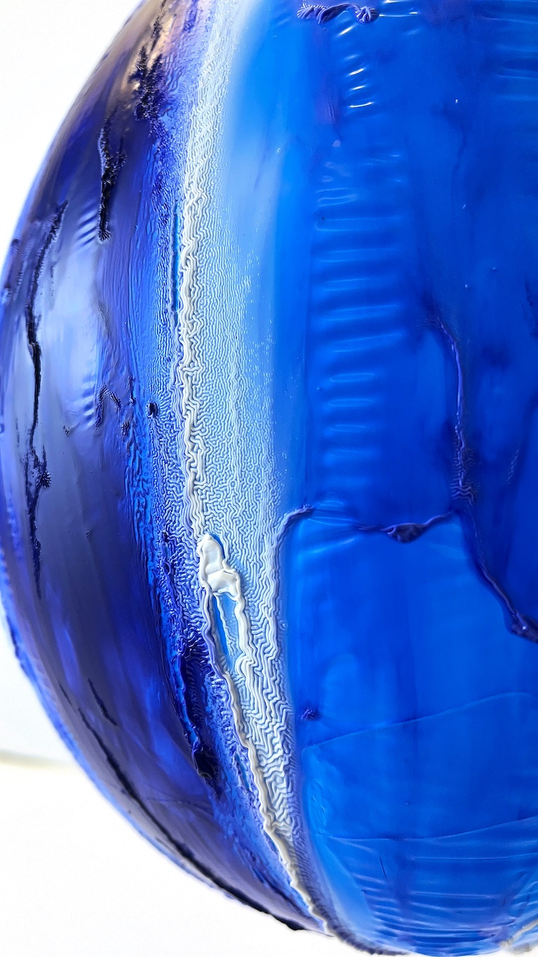 glossy curves in varying shades of blue form a convex surface with ridges, cracks, and striations