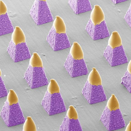 light pink pyramids on a grey plate with yellowish caps, lit from the upper right corner